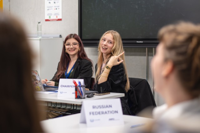 Chairpersons share a lighthearted moment behind the Russian Federation placard.