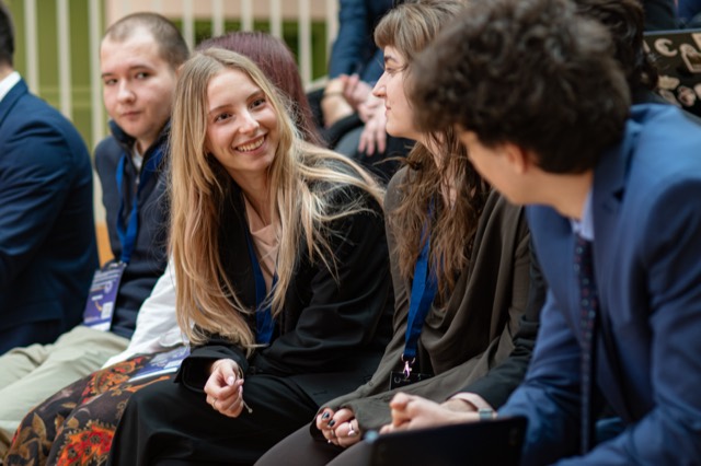 Seated delegates share a laugh while waiting during the ceremony.